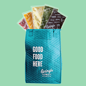 Image with light green background of turquoise back with frozen fruit and vegetable smoothies in the bag. The text on the bag is "Good food hear." by Living Farmacy Smoothie Subscription Canada.